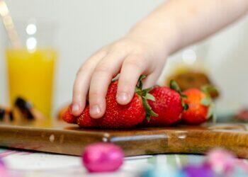 Kid reaching for strawberry (Unsplash | Ryland Dean)