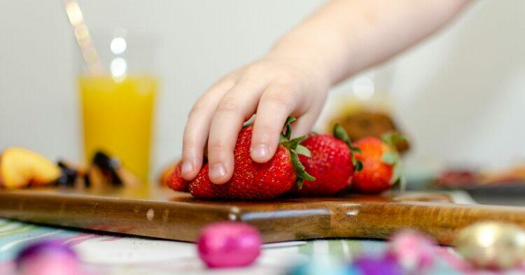 Kid reaching for strawberry (Unsplash | Ryland Dean)