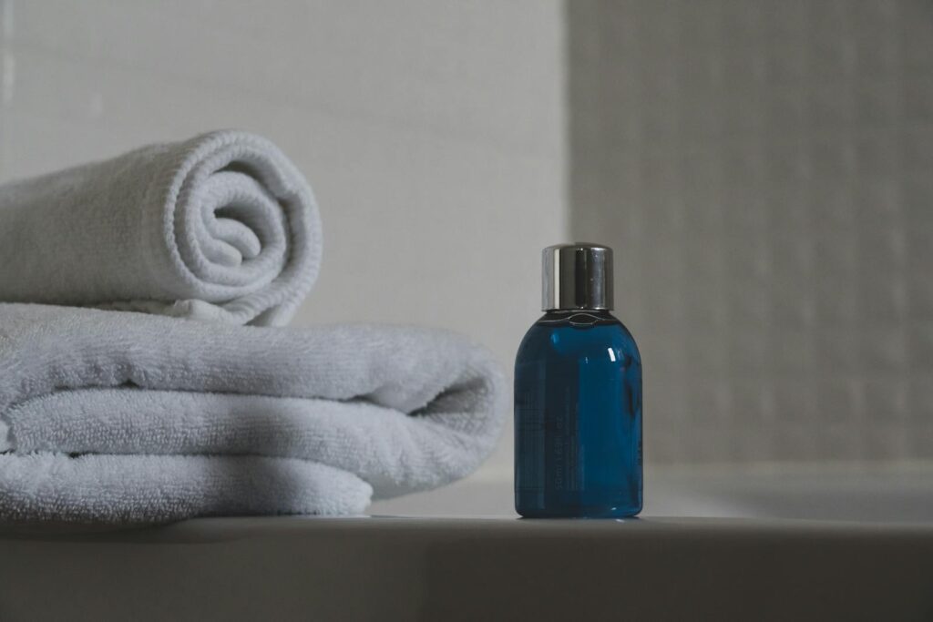A blue bottle sits in front of a stack of white towels