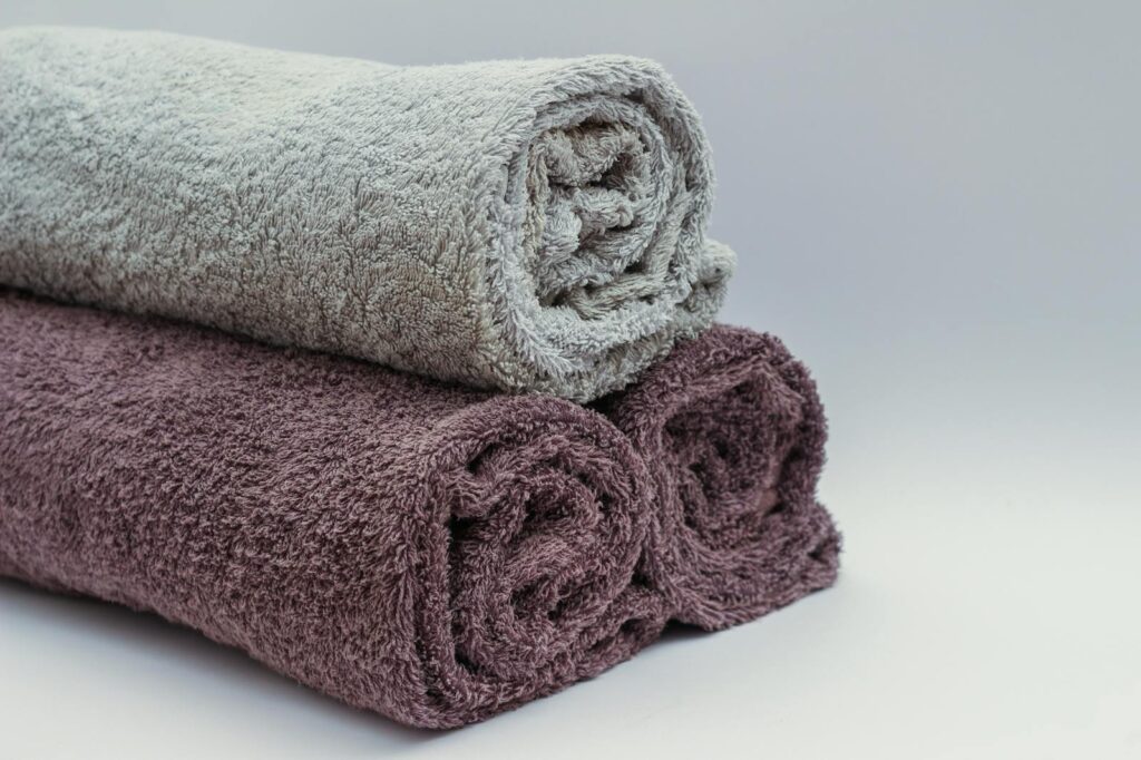White and maroon towels in a stack in front of a white background