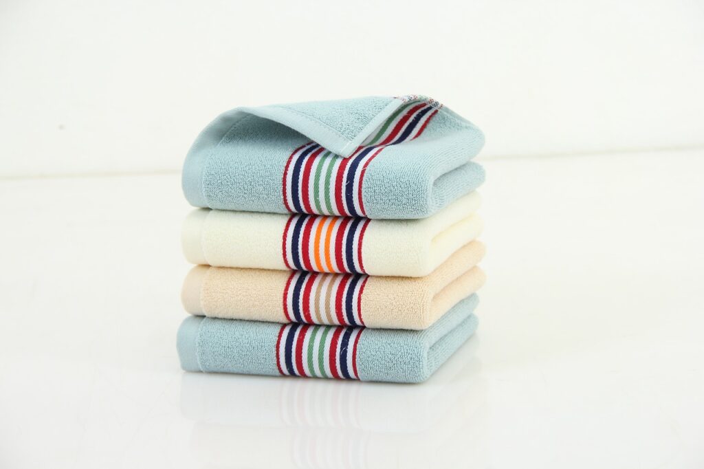 a pile of pastel colored towels sits in front of a white background
