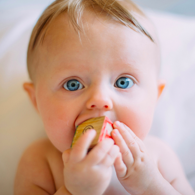 Baby teething on block