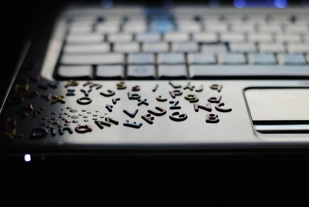 A computer with alphabet stickers stuck to the front of it.