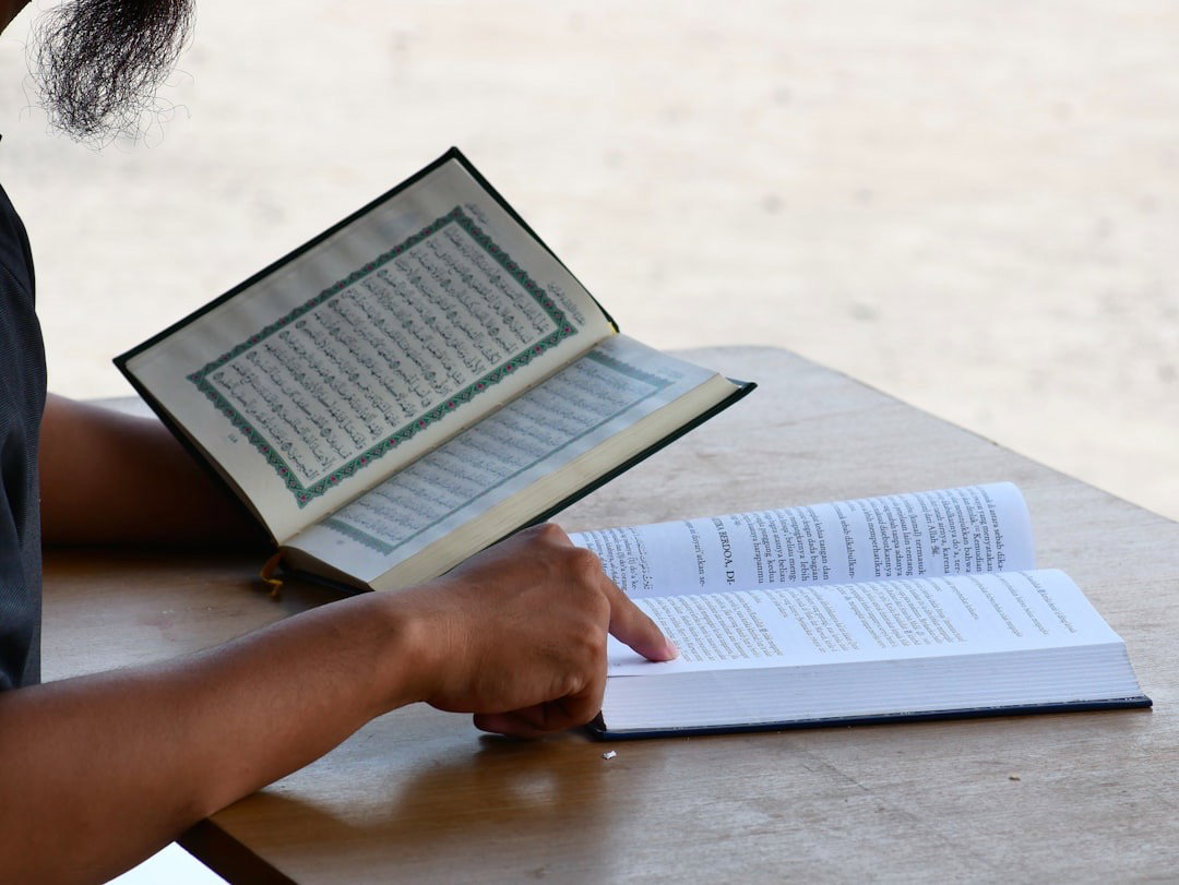 A person reading a textbook while holding another book.