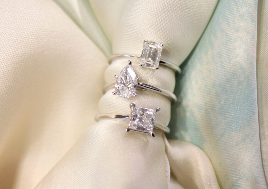 three diamond wedding rings on white satin