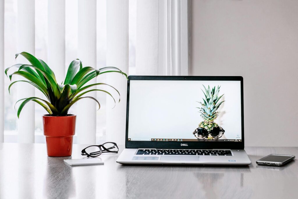 Photo of Laptop Near Plant on a. white table in front of white window blinds