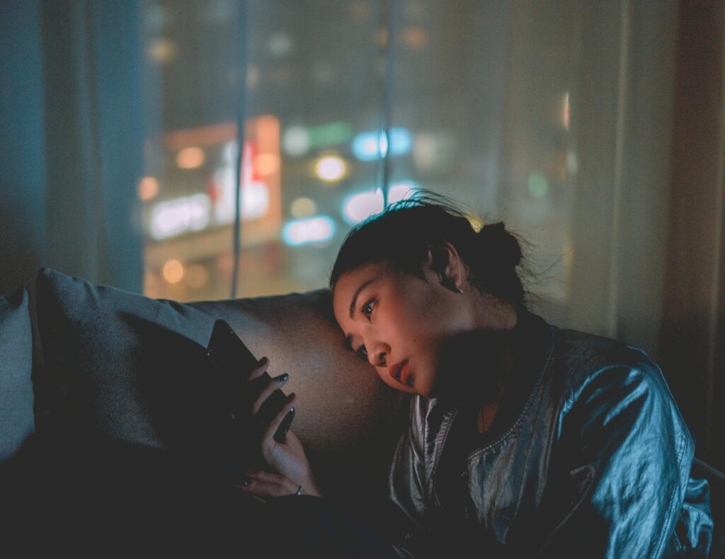 Photo Of Woman Using Mobile Phone next to a window at night