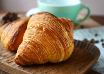 two croissants sitting on top of a wooden tray