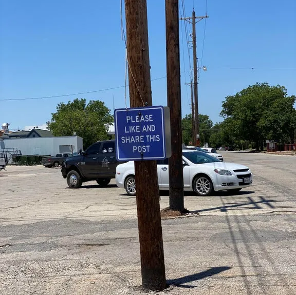 a sign on a post that says “please like and share this post”