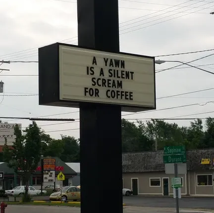 a sign that says “a yawn is a silent scream for coffee”