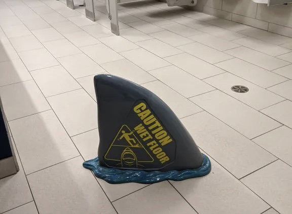 a wet floor sign in the shape of a shark fin