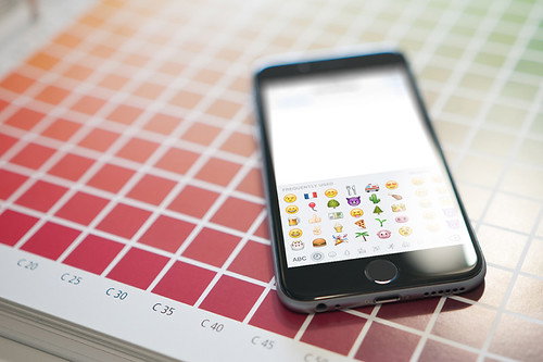 a phone with emojis sits on a table with colorful squares