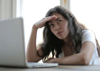 young annoyed female sitting in front of laptop