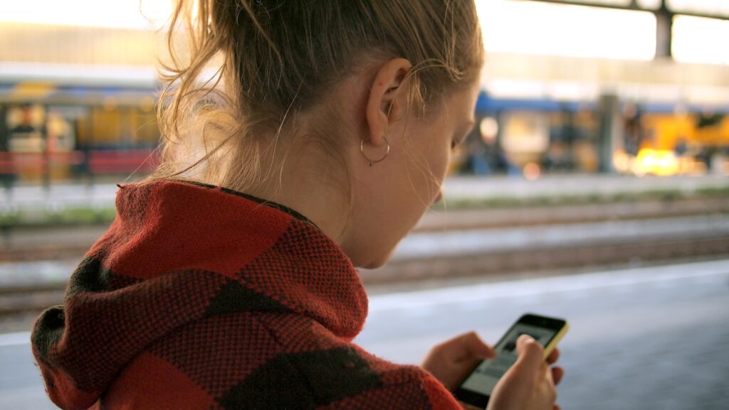 a woman with light hair holding a phone