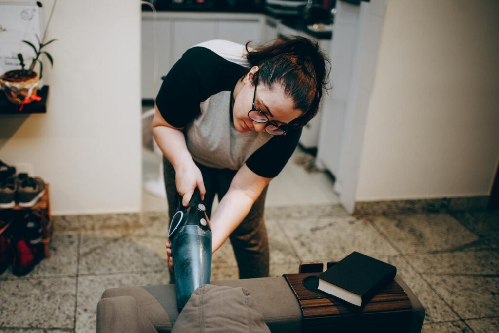 A woman is using a vacuum to clean a floor