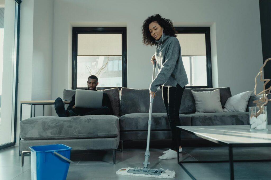 Woman in Gray Cardigan Standing Beside Gray Couch
