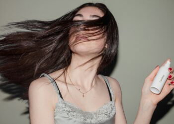woman holding a spray bottle with flowing hair in the air