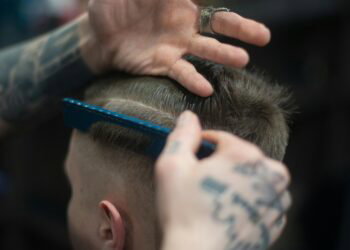 man with tattoos cutting another man's hair