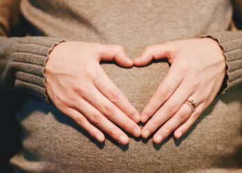 hands on a pregnant stomach forming a heart