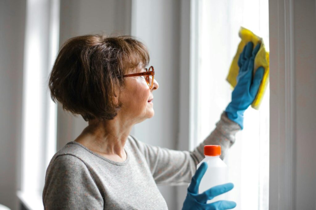 A woman with short brown hair cleaning a window