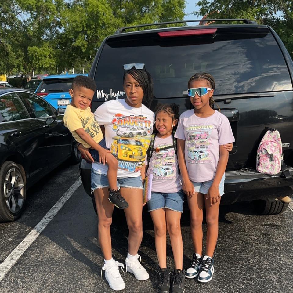 Taylor family posing near a car