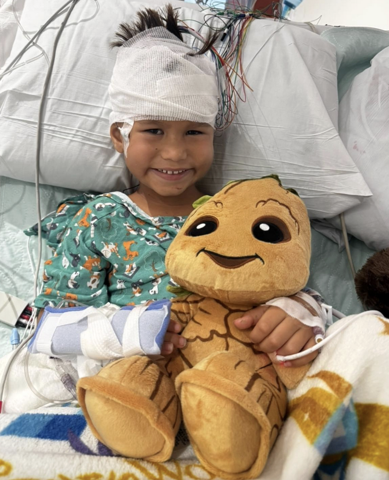 Child in hospital bed with a teddy bear