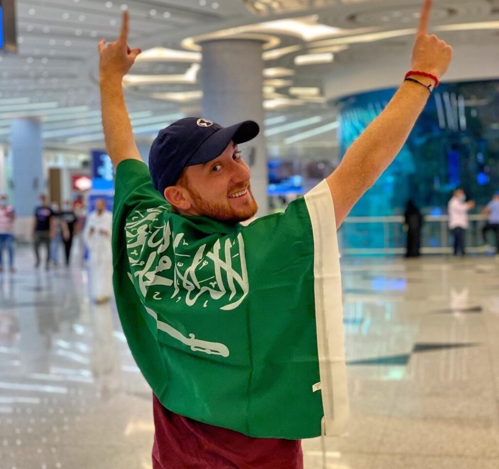 Drew Binsky drapped in a flag stepping foot in his 197th and final country, Saudi Arabia