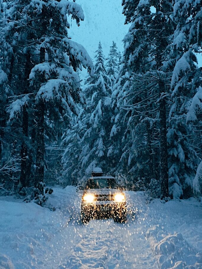 a car driving through a snow covered forest