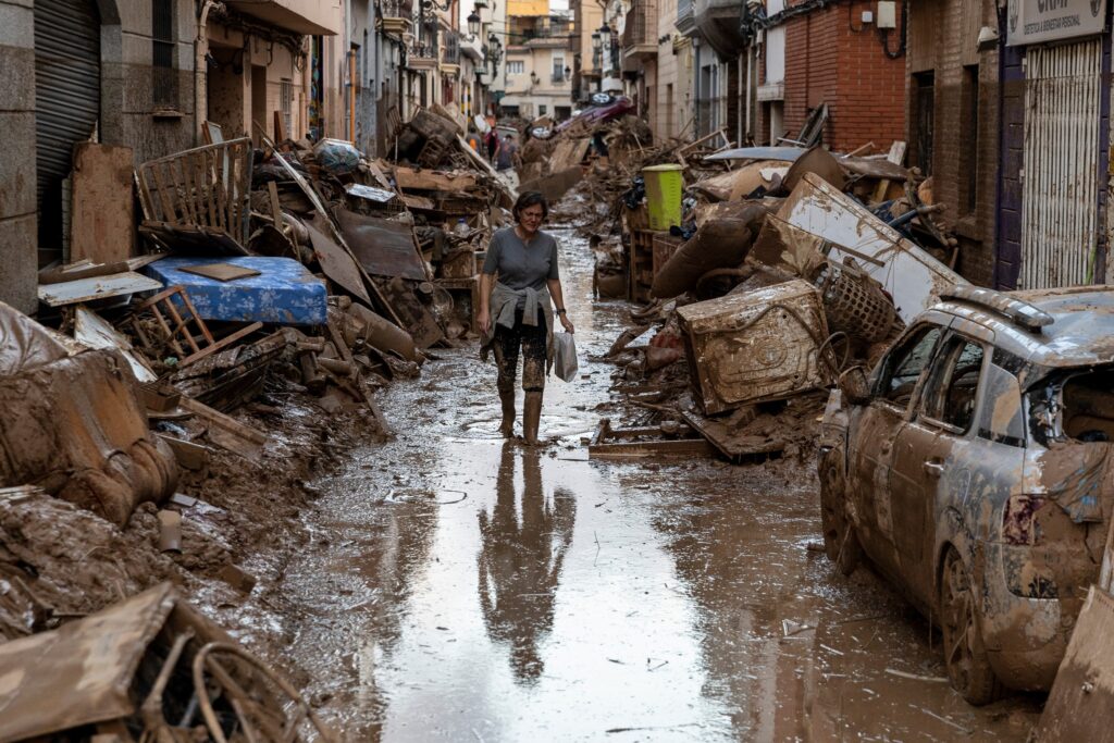 A woman walks through a street strewn with mud and debris from homes after heavy rain and flooding affected large areas of the country on November 2, 2024 in Paiporta, Valencia.