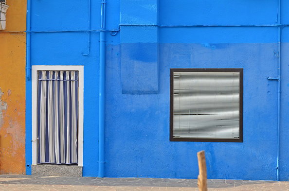 House with blue wall and blue curtains in front of the door
