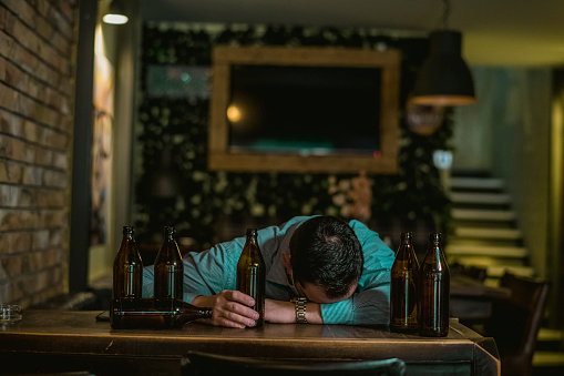 Young drunk man sleeping on bar counter