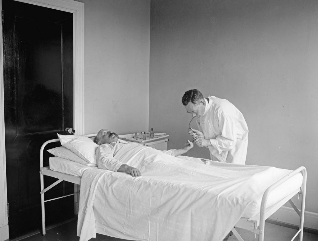 A doctor attending to a patient in a hospital ca. 1922