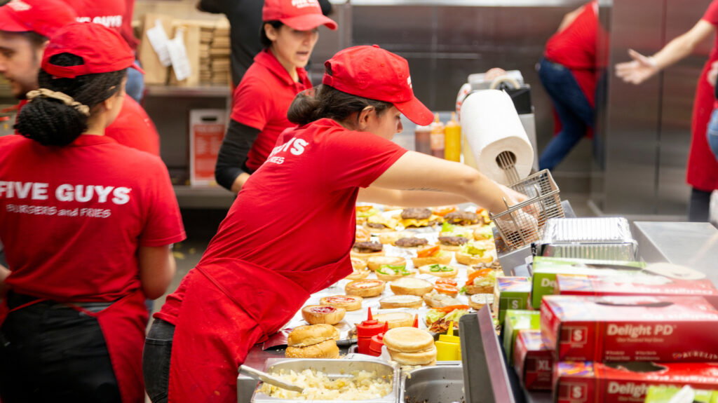 Five Guys workers prepare meals.