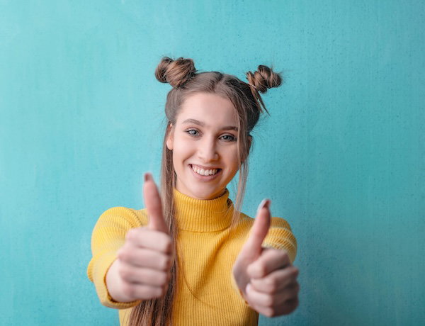 woman in a yellow top giving thumbs up
