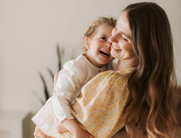 mother holding young daughter laughing together
