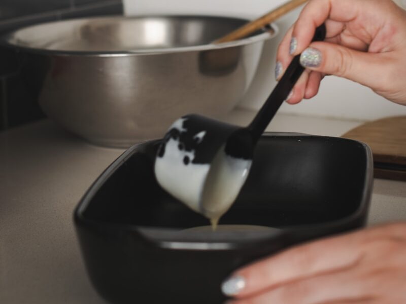 a person using a spatula to dip some food in a bowl