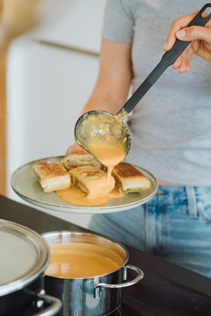 A woman is spooning some food on a plate