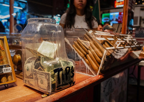 Tips in an open glass jar at a fair, cigar maker vendor booth
