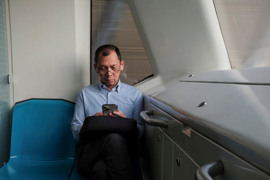 A man is seen texting on his phone at an MRT station in...