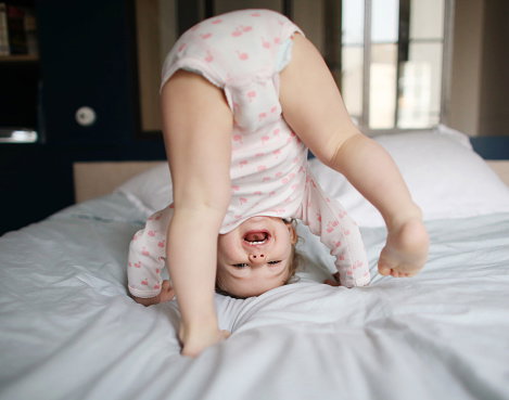 A baby girl playing on a bed