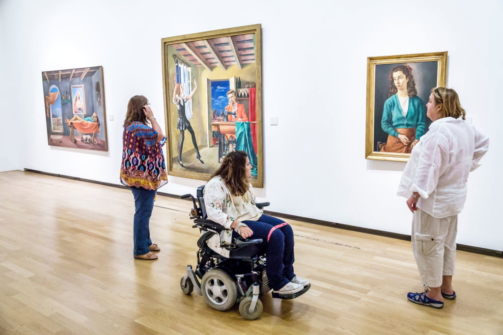 A girl in an electric wheelchair looking at Antonio Berni paintings at the National Museum of Fine Arts.