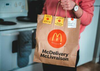 A person holding a McDelivery bag in a modern kitchen interior.
