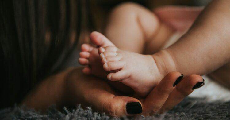 Mother holding baby's feet (Unsplash | Alex Pasarelu)