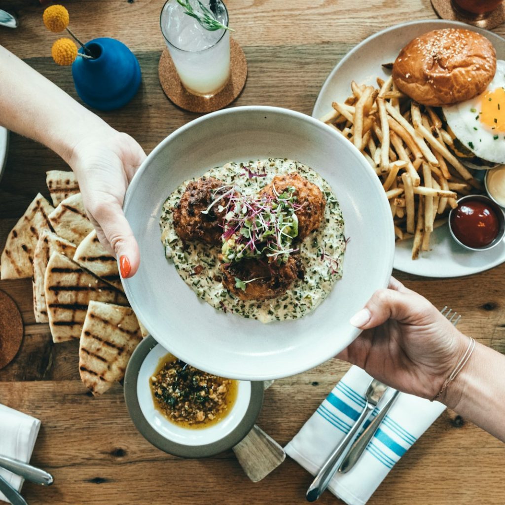 person holding white plate with food