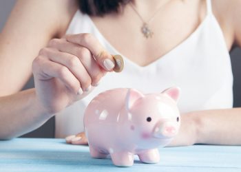 Woman putting coin in piggy bank