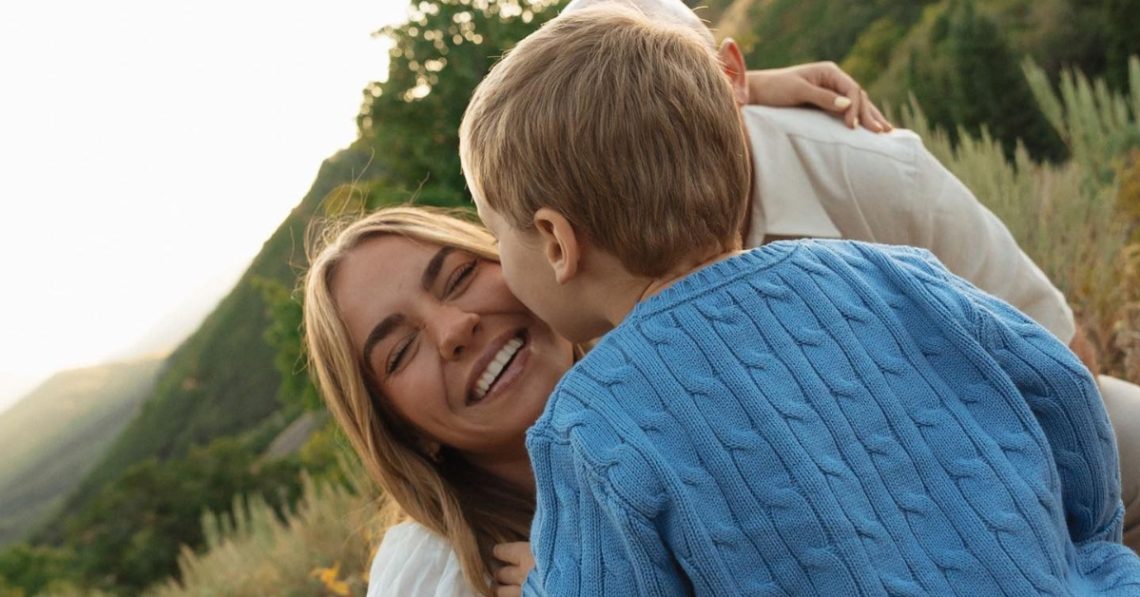 Emili Kiser with her husband and their son Trigg with Trigg kissing her on the cheek