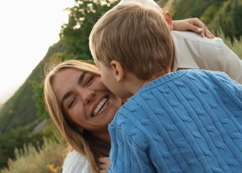 Emili Kiser with her husband and their son Trigg with Trigg kissing her on the cheek