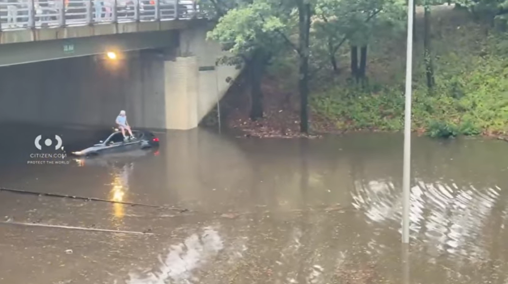 Person sitting on top of car in flood