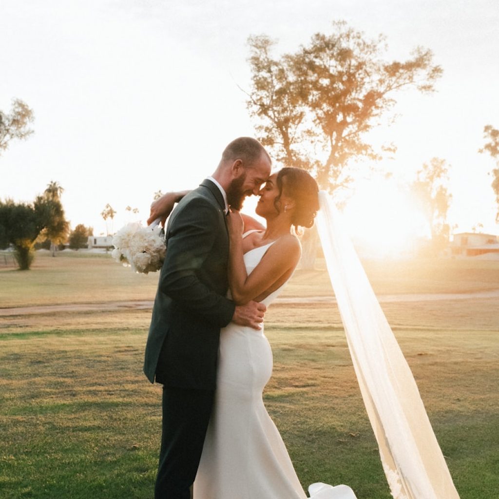 man and woman kissing on green grass field during sunset