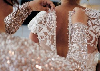 Someone zipping up bride dress